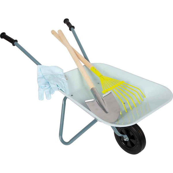 Eine Schubkarre aus Metall enthält ein Paar Gartenhandschuhe, eine Schaufel und eine gelbe Harke mit Holzgriffen.