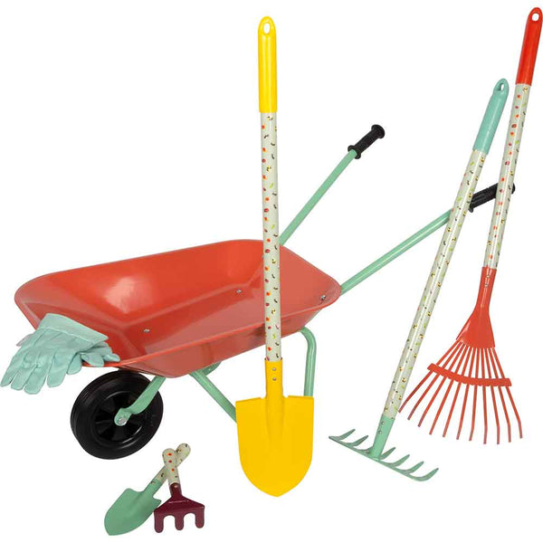 Eine rot-grüne Schubkarre ist mit Gartenhandschuhen, einer gelben Schaufel, einer Harke, einer Gabel und einer kleinen Kelle um sie herum angeordnet.
