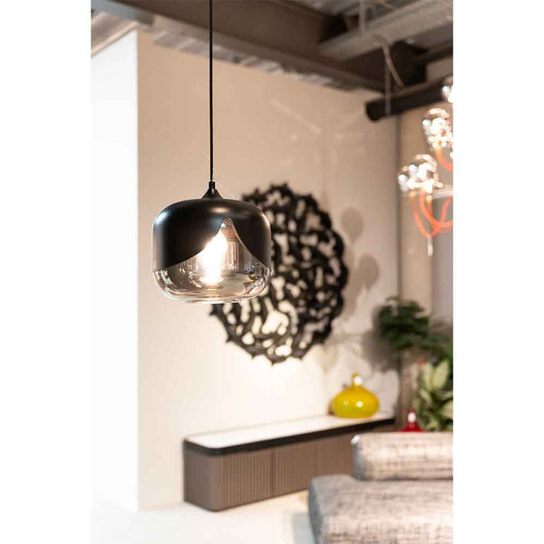 Eine moderne Pendelleuchte mit einem Schirm aus schwarzem Metall und Glas hängt in einem modernen Raum mit abstrakter Wandkunst, einem Sofa und dekorativen Akzenten.