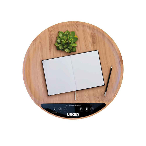 Runder Holztisch mit einer Sukkulente, einem aufgeschlagenen Notizbuch, einem Bleistift und einem UNOLD-Bedienfeld an der Vorderseite.