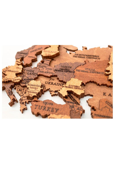 Eine Nahaufnahme eines hölzernen Kartenpuzzles, das Teile Europas und Westasiens zeigt, mit eingravierten Ländernamen wie Polen, Ukraine und Türkei.