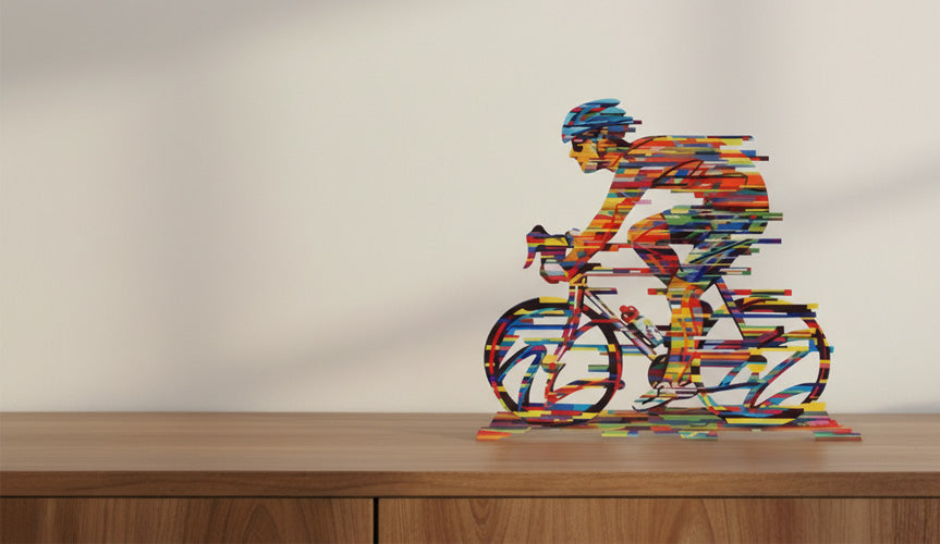 Bunte Skulptur eines Rennradfahrers steht auf einem Sideboard aus Holz