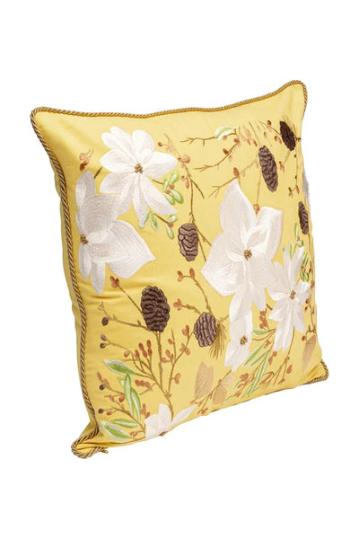 Quadratisches gelbes Kissen mit gestickten weißen Blumen, braunen Tannenzapfen und grünen Blättern, eingefasst von einer gedrehten Goldborte.