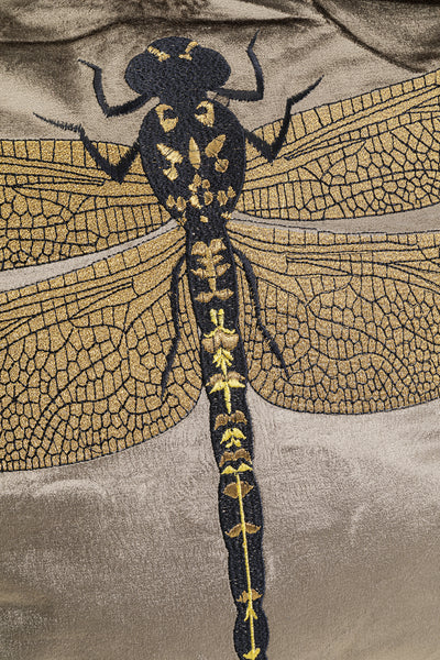 Gold- und schwarzgesticktes Libellenmuster auf einem strukturierten beigen Stoffhintergrund.