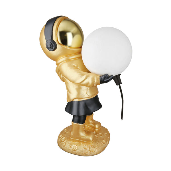 Goldene Astronautenfigur, die eine runde weiße Lampe mit schwarzer Schnur hält und auf einem strukturierten Sockel steht.