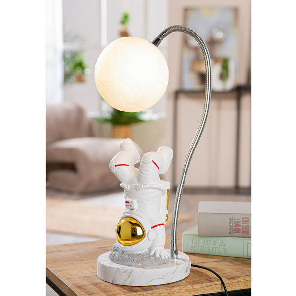 Astronautenlampe mit mondförmigem Licht, der Astronaut steht kopfüber auf einem Marmorsockel auf einem Tisch.