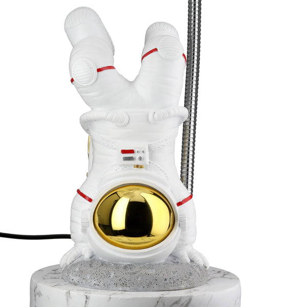 Eine kleine Astronautenfigur, die einen Handstand auf einem runden Sockel macht, mit einem goldenen Helm und weißem Anzug.