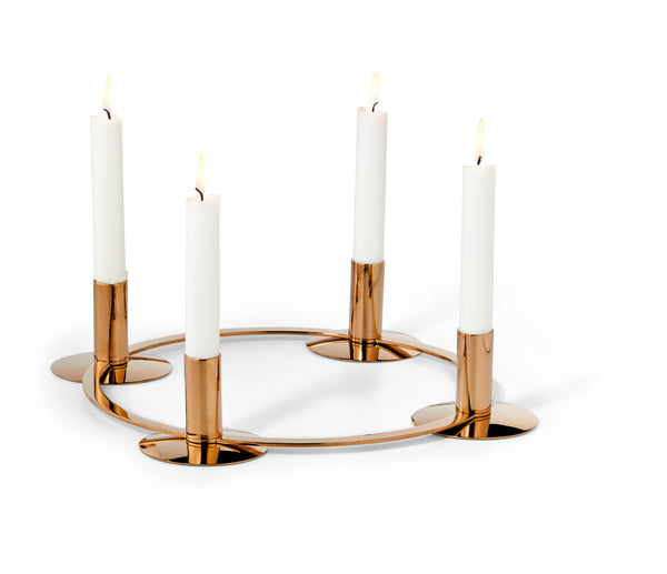 Ein runder, goldener Kerzenhalter mit vier brennenden weißen Kerzen, die in gleichen Abständen aufgestellt sind.