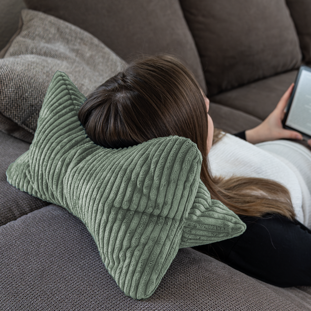 Eine Person lehnte sich entspannt auf dem Leseknochen Cozy Shara - Salbei zurück und liest komfortabel auf einem e-Reader – perfekter Lesekomfort.