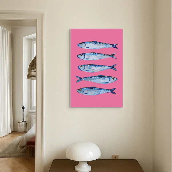 Ein Gemälde mit vier blauen Fischen auf rosa Hintergrund hängt an einer cremefarbenen Wand über einer weißen Lampe.