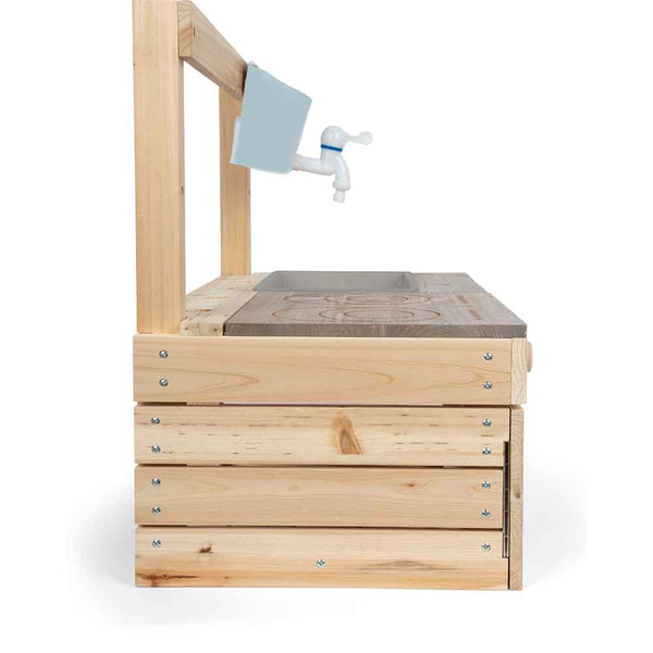 Seitenansicht einer hölzernen Spielküche mit einem Wasserhahn, einem blauen Griff und einer Arbeitsplatte mit einem geschnitzten Brennermotiv.