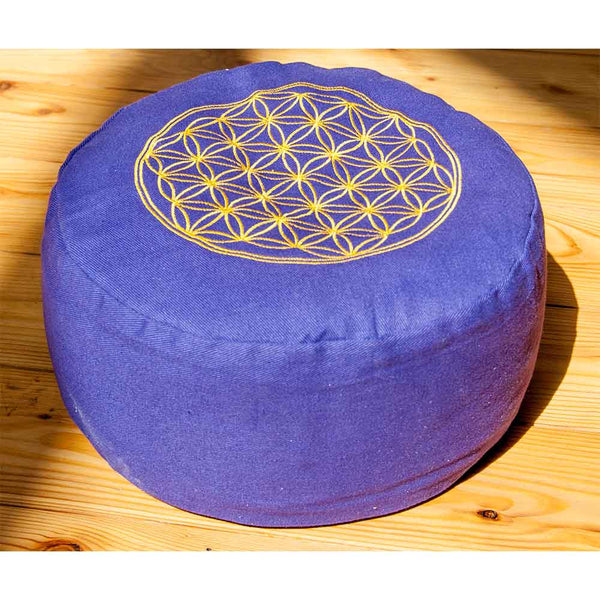 Ein rundes violettes Meditationskissen mit einem gelben geometrischen Muster liegt auf einem Holzboden.