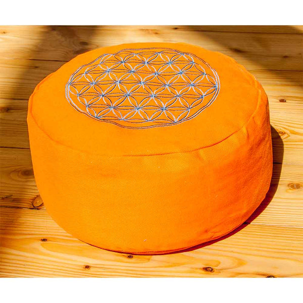 Leuchtend orangefarbenes, rundes Kissen mit einem geometrischen Blumenmuster auf der Oberseite, platziert auf einem Holzboden.