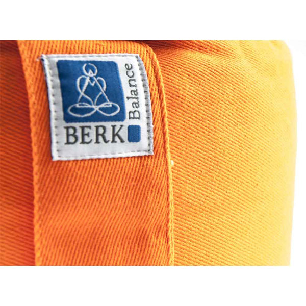 Nahaufnahme eines orangefarbenen Stoffes mit einem BERK Balance-Etikett, auf dem eine meditierende Figur abgebildet ist.