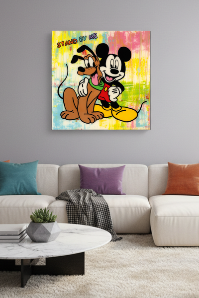 Das Kunstwerk, auf dem Mickey Mouse mit dem Arm um Pluto vor einem farbenfrohen, abstrakten Hintergrund zu sehen ist, über dem die Worte STAND BY ME stehen, hängt im Wohnzimmer über der Couch.