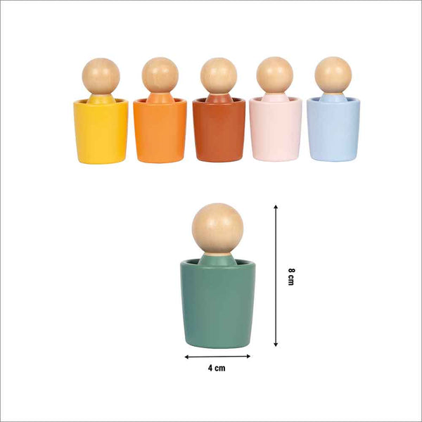 Abgebildet sind fünf Holzpuppen in farbigen Bechern, darunter ein grüner Becher mit den Maßen 8 cm hoch und 4 cm breit.