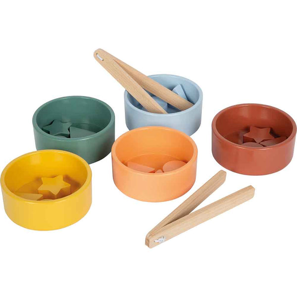 Fünf farbige Schalen enthalten jeweils verschiedene Holzteile und eine Holzzange, die vor die Schalen gestellt wird.