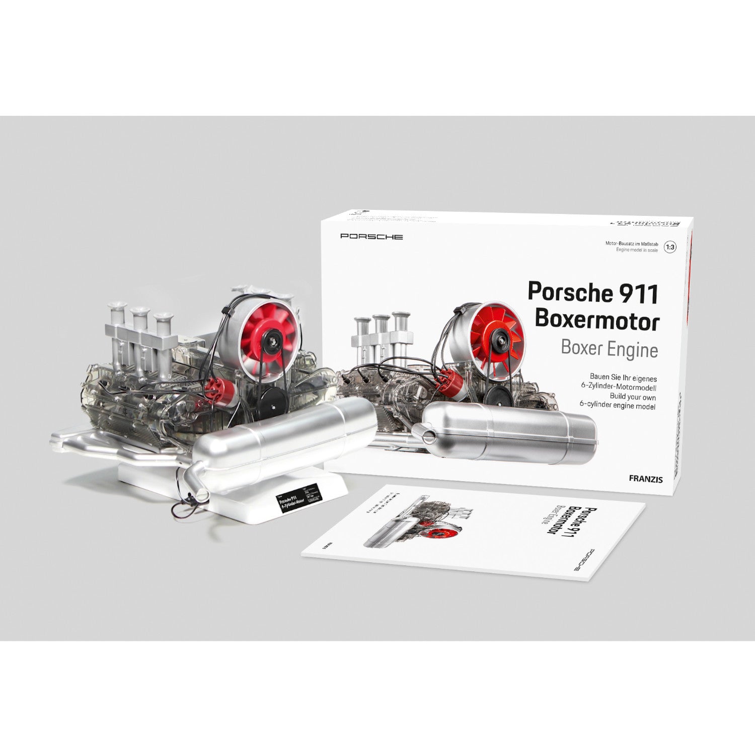 Modell Porsche 911 Boxer-Motor mit roten Ventilatoren, neben seiner Box und Bedienungsanleitung auf einem weißen Hintergrund angezeigt.