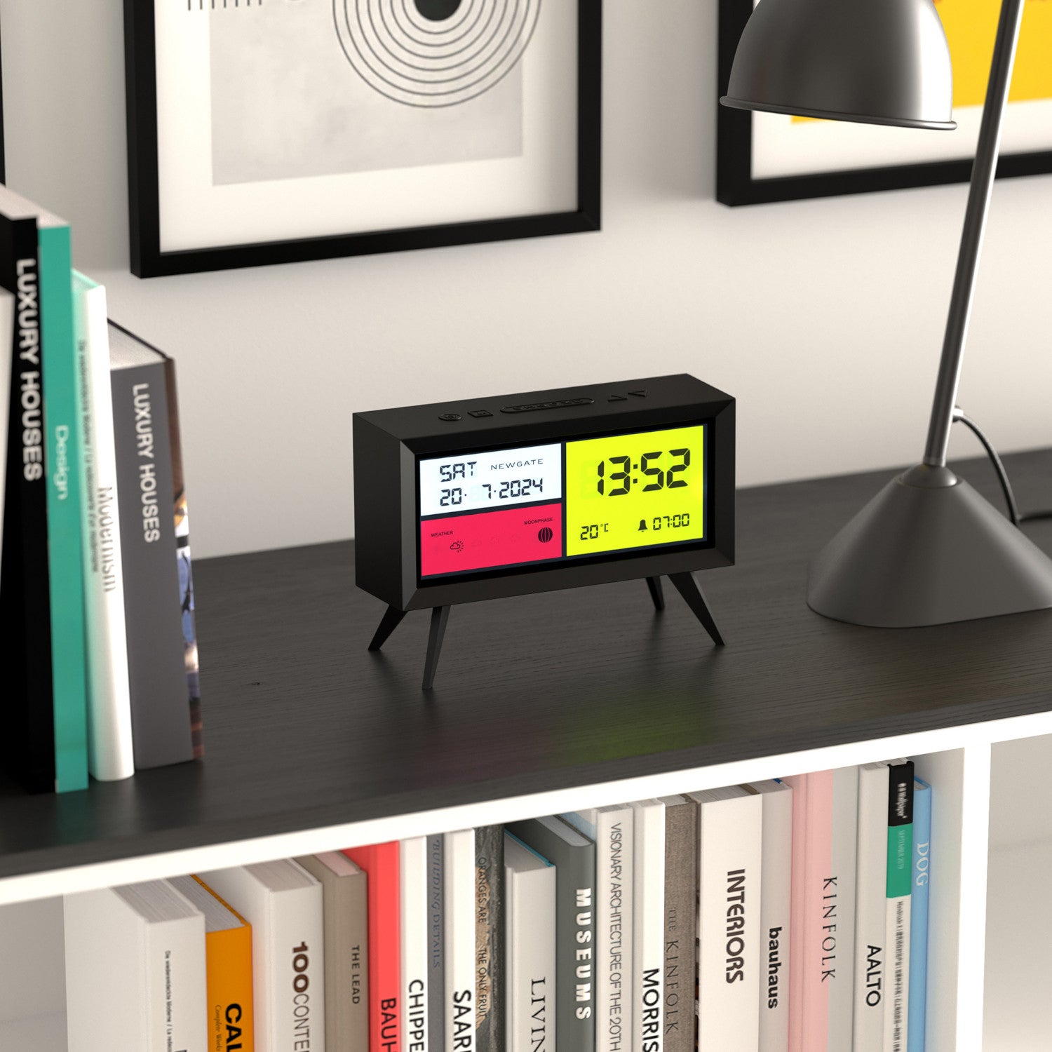 Digitaluhr auf einem schwarzen Regal, umgeben von Büchern, unter einer Schreibtischlampe und Wandkunst.