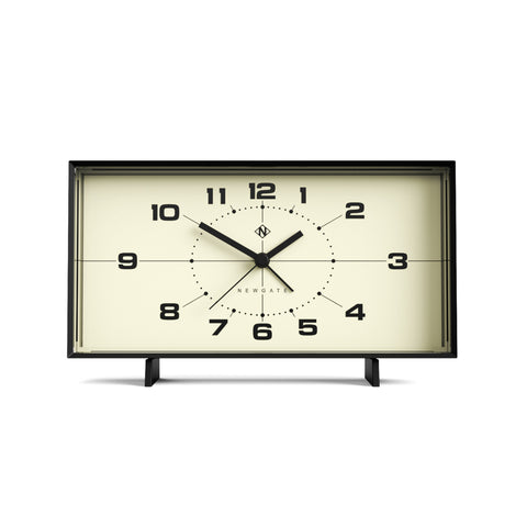 Rechteckige, schwarz gerahmte Uhr mit schwarzen Zahlen und Zeigern, die die Uhrzeit 10:10 anzeigen.