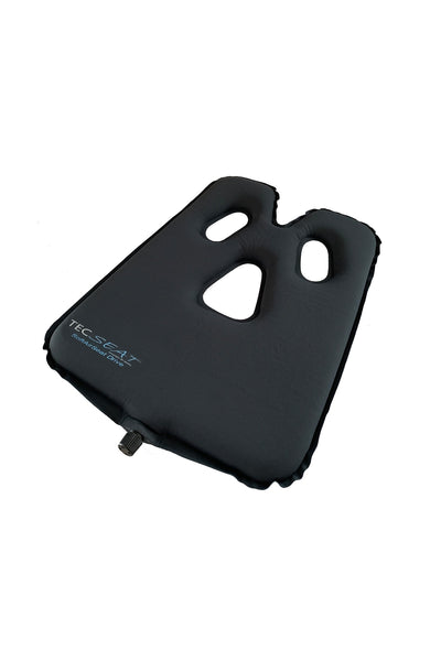 Schwarzes Kissen mit drei ausgeschnittenen Löchern, leicht erhöhten Kanten und einem kleinen Ventil an einer Seite. Das Tecseat-Branding ist in einer Ecke sichtbar.