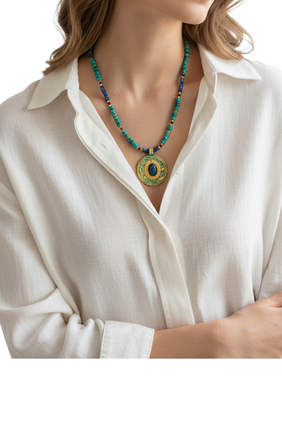 Perlenkette mit einem großen, verzierten runden Anhänger in Gold und Blau mit einem altägyptischen Skarabäus an einem Hals einer Dame mit weißer Bluse