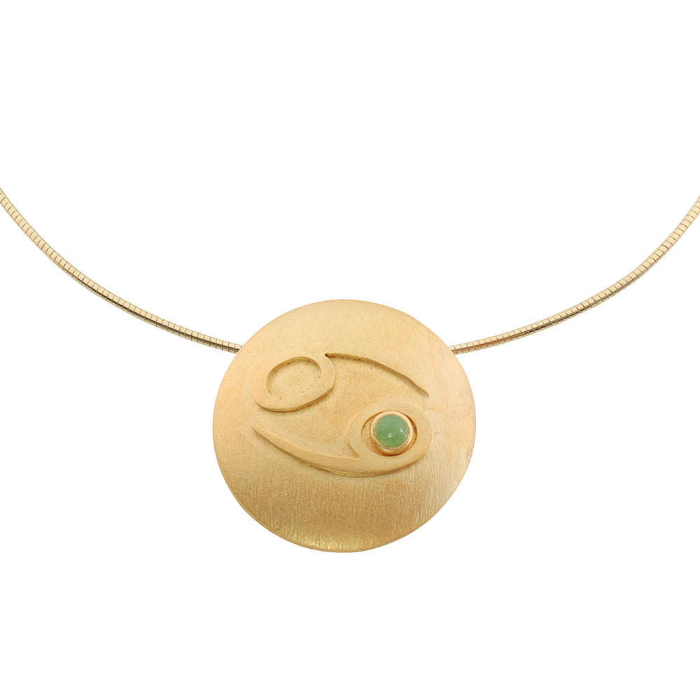 Petra Waszak: Sternzeichen-Collier „Krebs“ (22.06.-22.07.) – eine goldene Halskette mit einem runden Krebs-Sternzeichen-Anhänger, der mit einem kleinen grünen Edelstein-Akzent verziert ist.