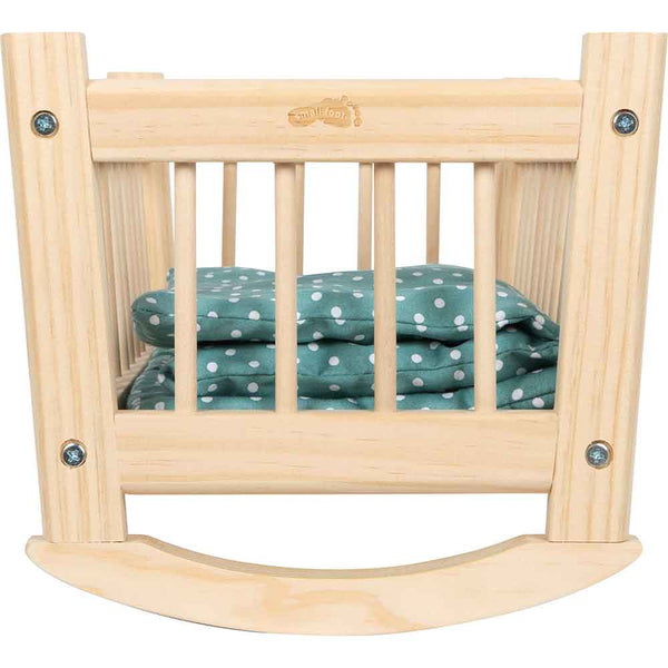 Ein schaukelndes Puppenbettchen aus Holz mit grüner Tupfenbettwäsche.