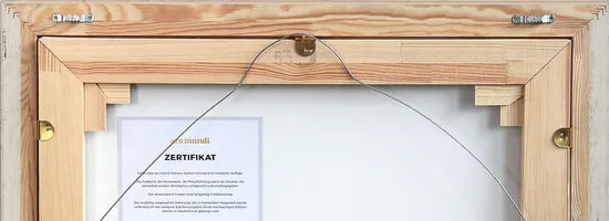 Rückseite eines hölzernen Bilderrahmens mit Aufhängedraht und sichtbarem Zertifikat im Inneren.