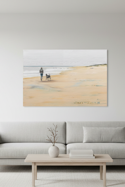 Das Gemälde mit einer Person und ein Hund gehen unter einem bewölkten Himmel an einem ruhigen Sandstrand entlang - platziert in einem Wohnraum an der Wand hängend. 