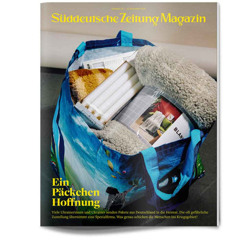 Eine blaue Einkaufstasche, gefüllt mit gerollten Papieren, Zeitschriften und einer Fleecedecke auf dem Cover des Süddeutsche Zeitung Magazins.