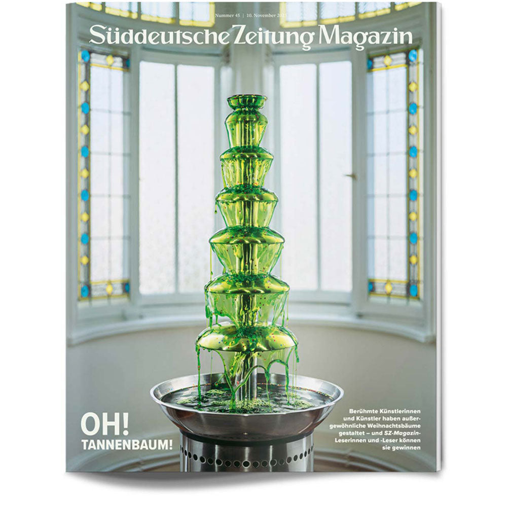 Ein stufenförmiger grüner Schokoladenbrunnen steht vor hohen, gewölbten Fenstern auf einem Zeitschriftencover.
