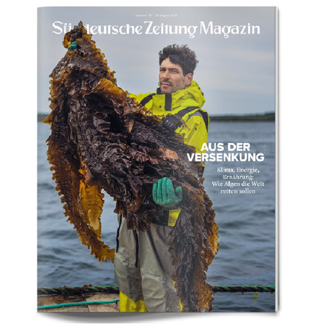 Ein Mann in einem gelben Regenmantel hält einen großen Seetang auf einem Zeitschriftencover mit einem deutschen Text über Klima und Energie.