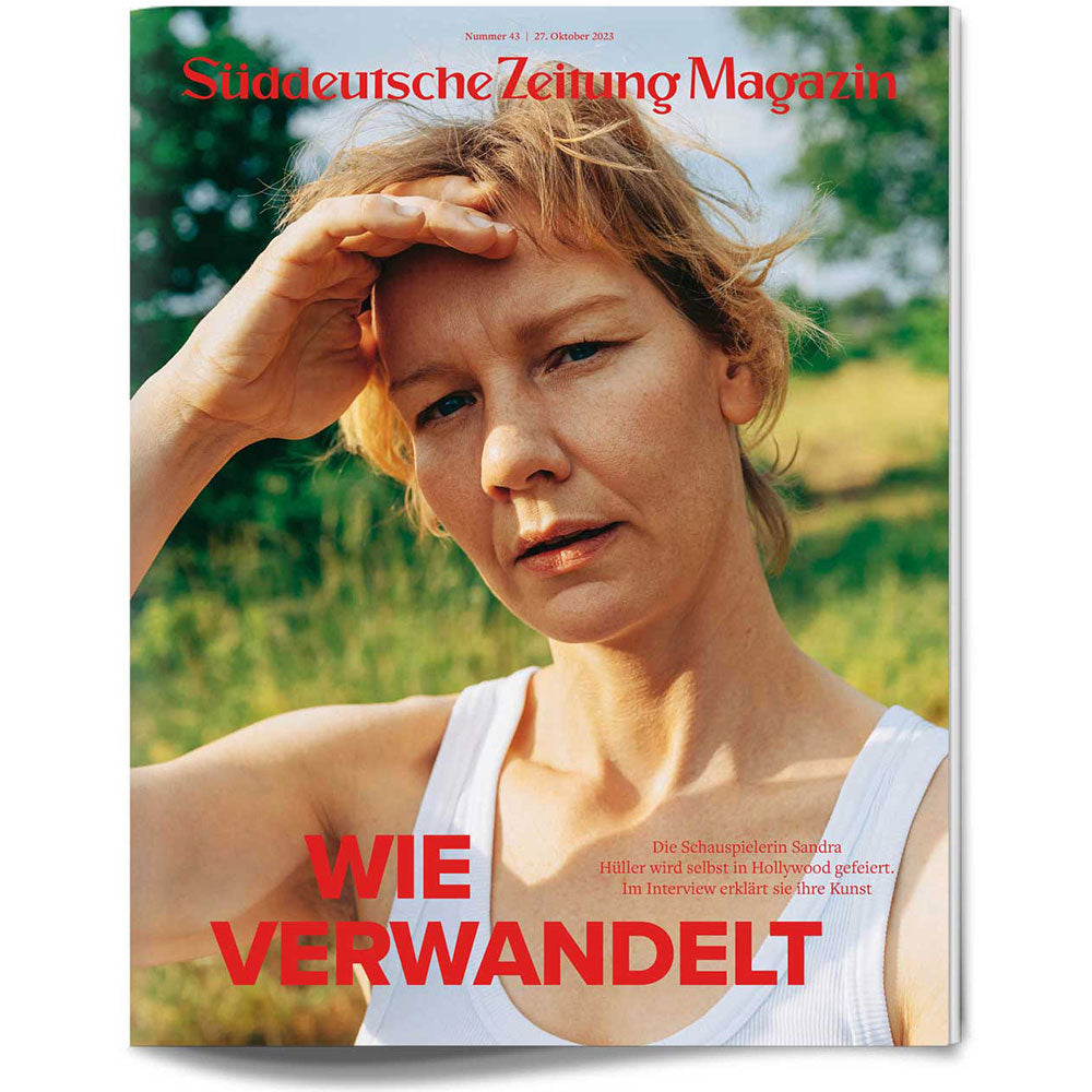 Eine Frau in einem weißen Tank-Top steht im Freien und schirmt ihre Augen mit der Hand vor der Sonne ab.