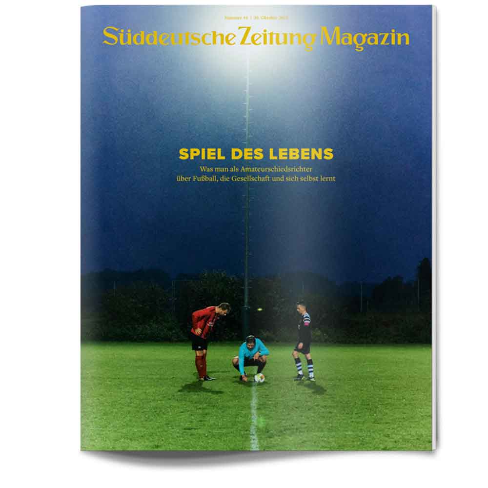 Drei Fußballspieler stehen nachts auf einem hell erleuchteten Feld unter einem dunklen Himmel, bereit zum Anstoß.