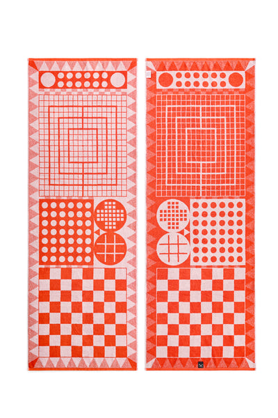 Ein  rotes  Badetuch Vorderseite und Rückseite  mit verschiedenen klassischen Brettspielmustern, darunter Schach, Dame und Tic-Tac-Toe.