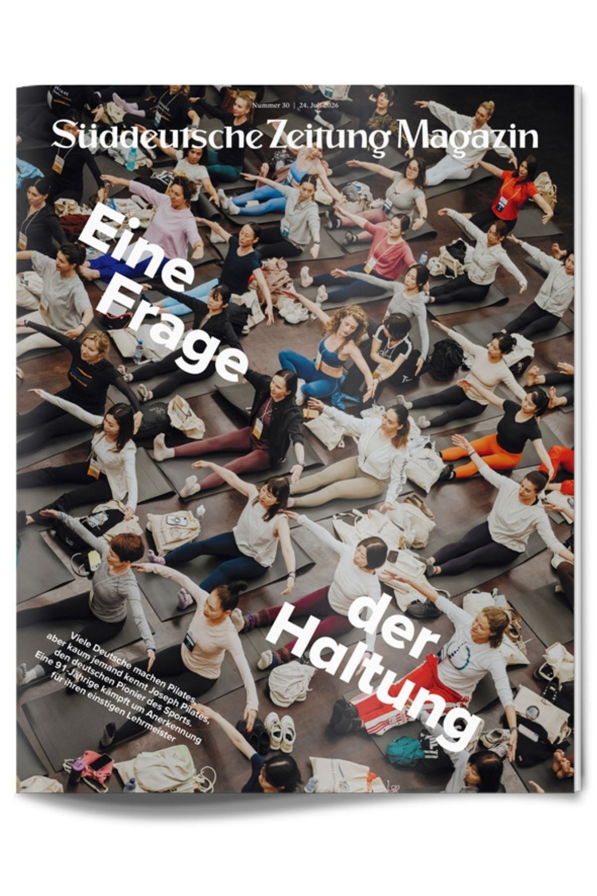 Eine große Gruppe von Menschen nimmt in einem Raum auf Matten an einem synchronisierten Yoga-Kurs teil. Der Titel der Zeitschrift und der deutsche Überschriftentext sind über das Bild gelegt.