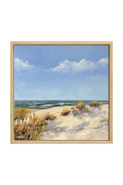 Gemälde eines Sandstrandes mit grasbewachsenen Dünen im Vordergrund, Wellen im Meer und einem blauen Himmel mit ein paar Wolken, gerahmt in hellem Holz.