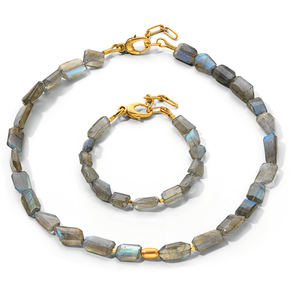 Das Schmuckset „Meeresschillern“ besteht aus einer Halskette und einem Armband mit Goldverschluss und unregelmäßigen Labradoritperlen auf weißem Hintergrund.
