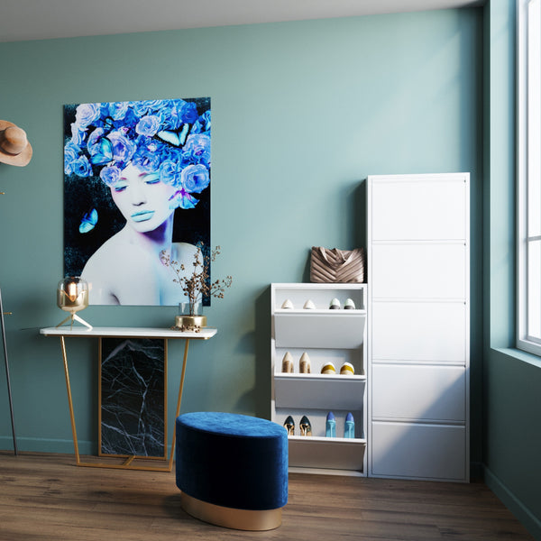 Modernes Zimmer mit blauen Wänden, einem Bild einer Frau mit Blumen, weißen Schuhregalen und einem runden blauen Hocker.