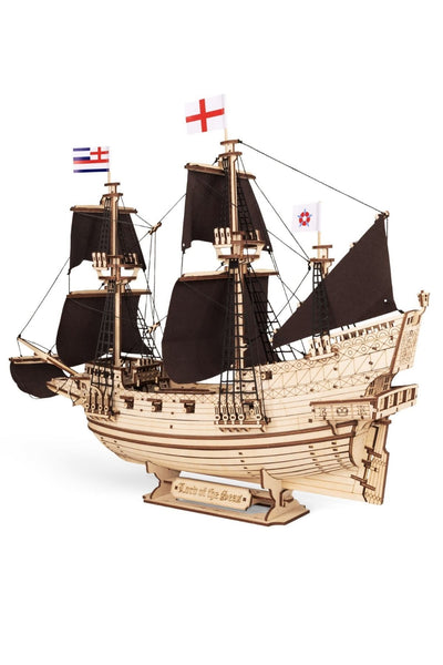 Ein hölzernes Modell eines Segelschiffs mit schwarzen Segeln, drei Masten und drei Flaggen, das auf einem Ständer mit der Aufschrift Lord of the Seas steht.