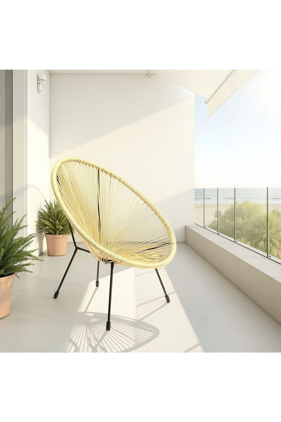 Ein runder, gelber Flechtstuhl mit schwarzen Beinen steht auf einem geräumigen Balkon mit Meerblick, flankiert von Topfpflanzen.