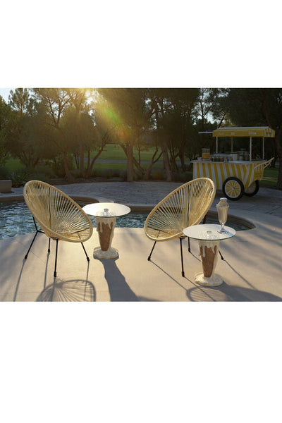 Zwei Korbstühle und kleine runde Tische stehen an einem Pool, auf den Tischen stehen Getränke und im Hintergrund steht ein gelb gestreifter Wagen, der von Bäumen umgeben ist.