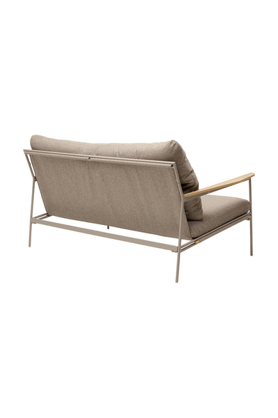 Ein modernes Sofa mit Metallgestell, beigen Kissen und Armlehnen aus Holz, schräg von hinten gesehen vor einem weißen Hintergrund.