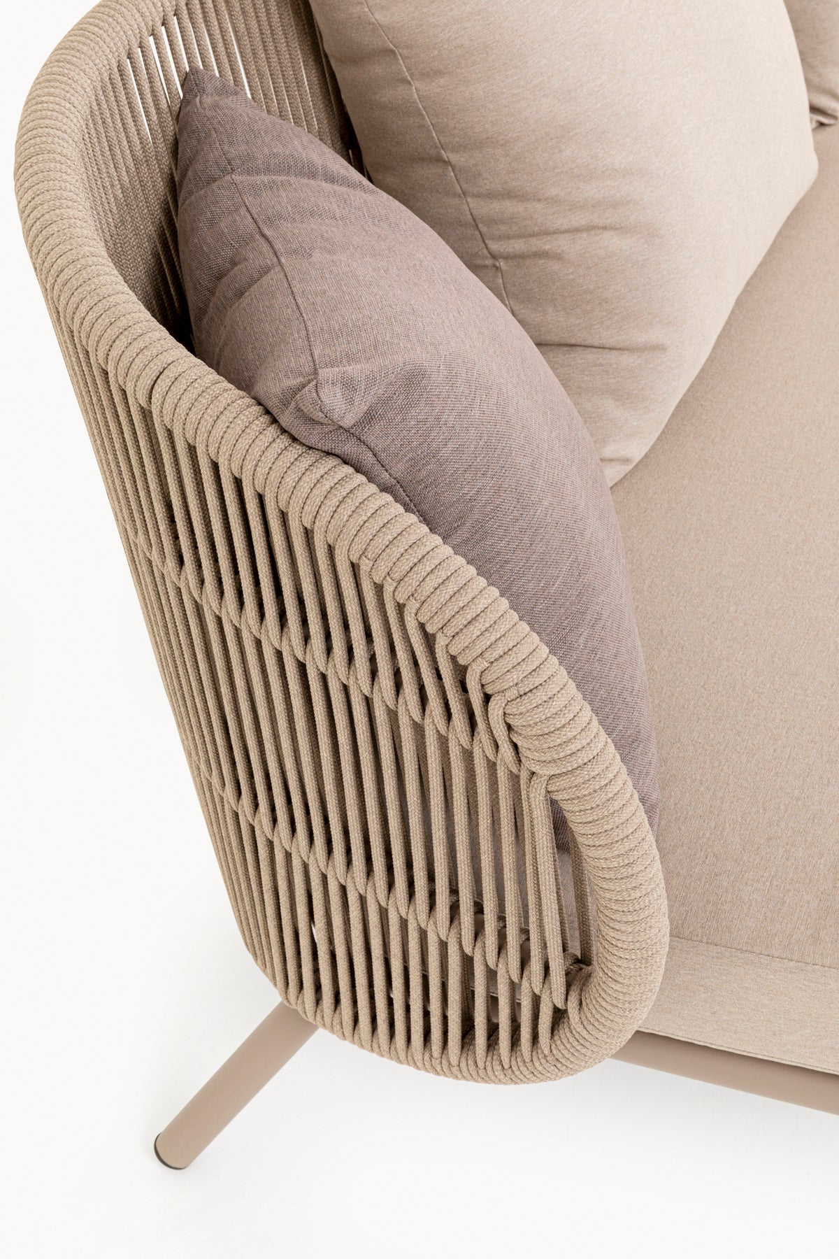 Nahaufnahme eines beigefarbenen, geflochtenen Sofas für den Außenbereich mit taupefarbenen Kissen und Metallbeinen, das ein detailliertes Design der Armlehnen im Seilstil zeigt.