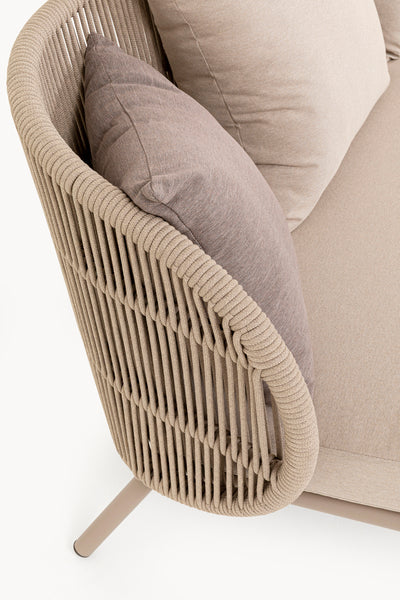 Nahaufnahme eines beigefarbenen, geflochtenen Sofas für den Außenbereich mit taupefarbenen Kissen und Metallbeinen, das ein detailliertes Design der Armlehnen im Seilstil zeigt.