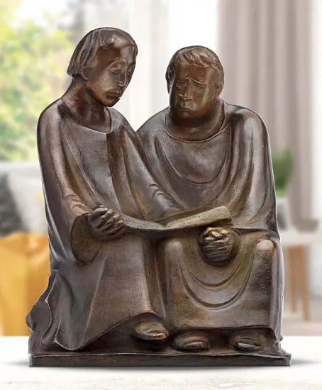 Bronzeskulptur von zwei sitzenden Figuren, die gemeinsam ein aufgeschlagenes Buch auf dem Schoß lesen.