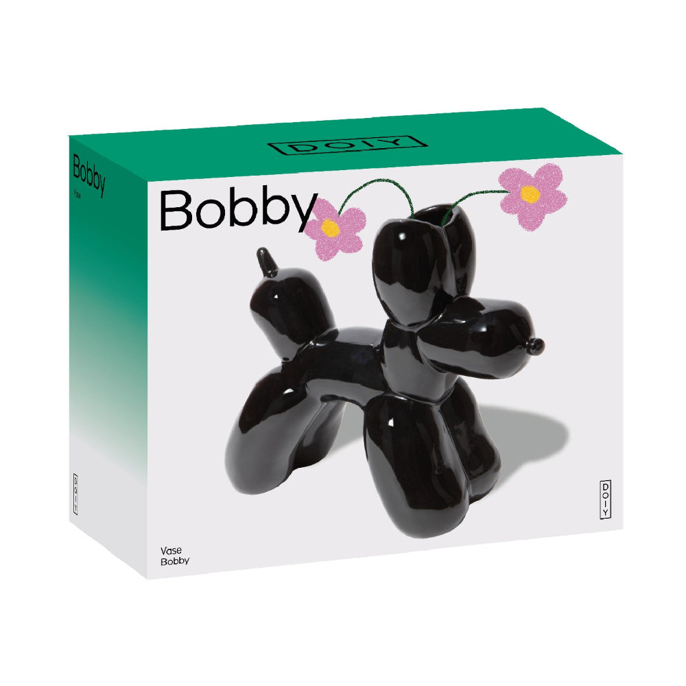 Ein Produktkarton mit einer schwarzen Vase in Form eines Ballonhundes mit der Aufschrift "Bobby" und rosa Cartoon-Blumen in den Öffnungen der Vase.