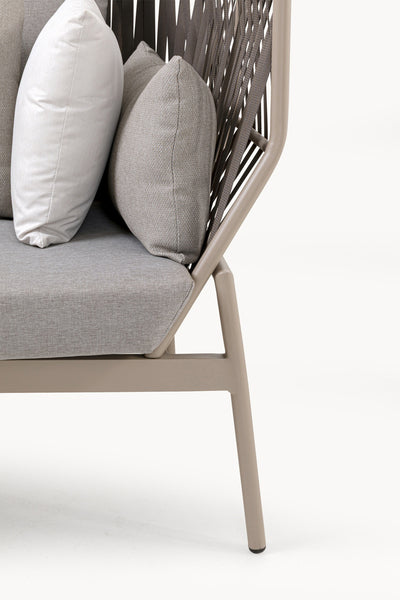 Nahaufnahme eines modernen Stuhls mit hellbeigem Gestell, grauer geflochtener Rückenlehne, grauem Sitzkissen und drei Kissen in verschiedenen Grau- und Weißtönen.