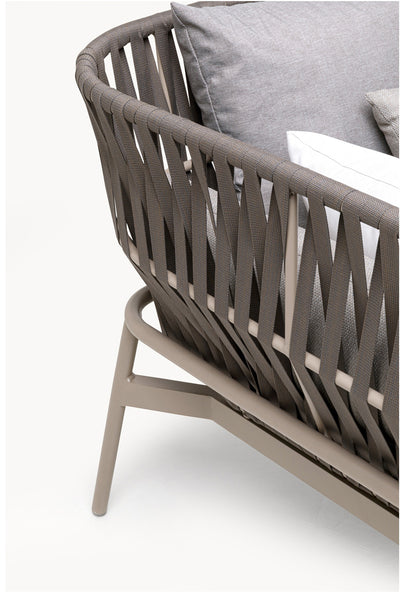 Nahaufnahme eines modernen Outdoor-Stuhls mit taupefarbenen geflochtenen Gurten und Metallgestell, mit hellgrauen und weißen Kissen.